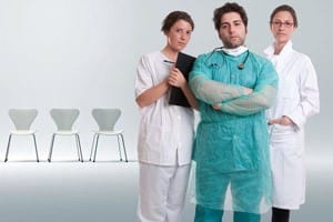 Three doctors standing together in front of chairs