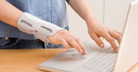 person with hand brace typing on a laptop